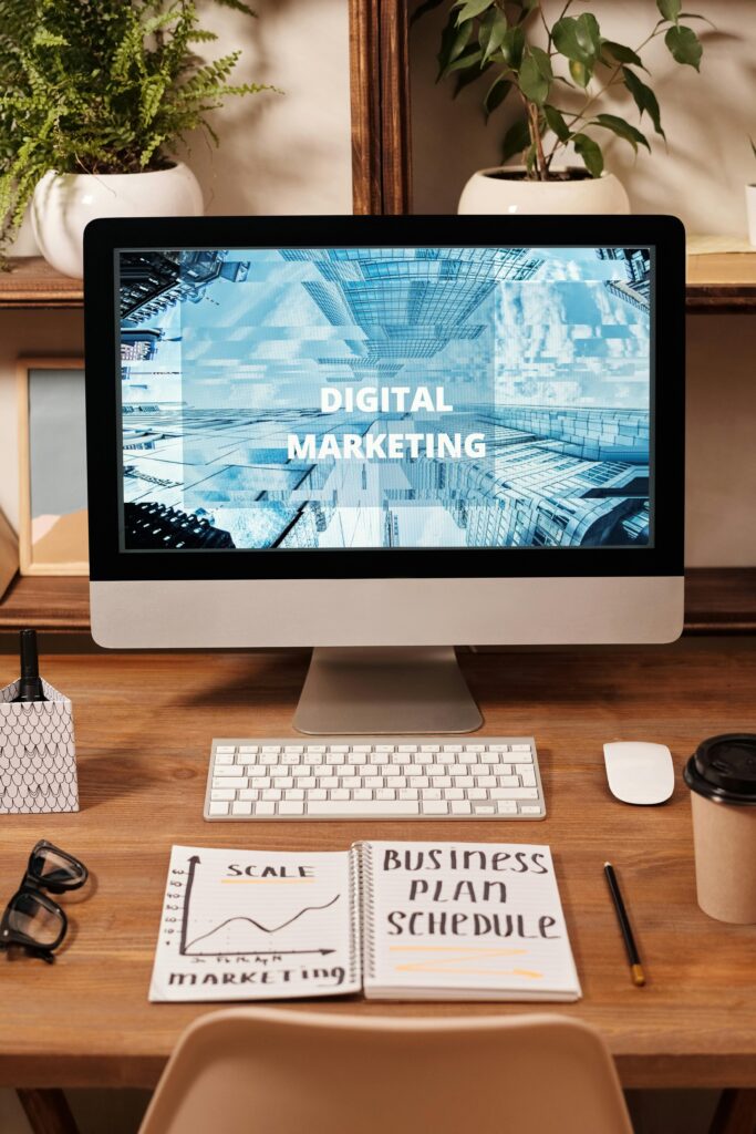 A business plan schedule written on a notebook with a desktop monitor showing digital agency for digital agencies hosting kenya